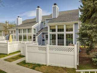 Discover this charming townhome featuring a beautiful exterior with a light blue siding and a white fence.
