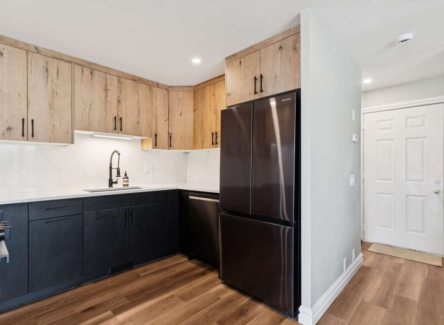 This stunning kitchen boasts modern design with its sleek black cabinetry and elegant wood-toned upper cabinets.