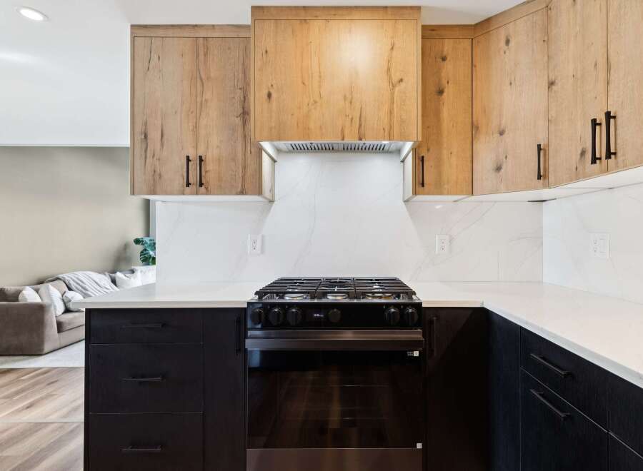 This modern kitchen boasts a sleek design with dark cabinetry and light countertops, creating a striking contrast.