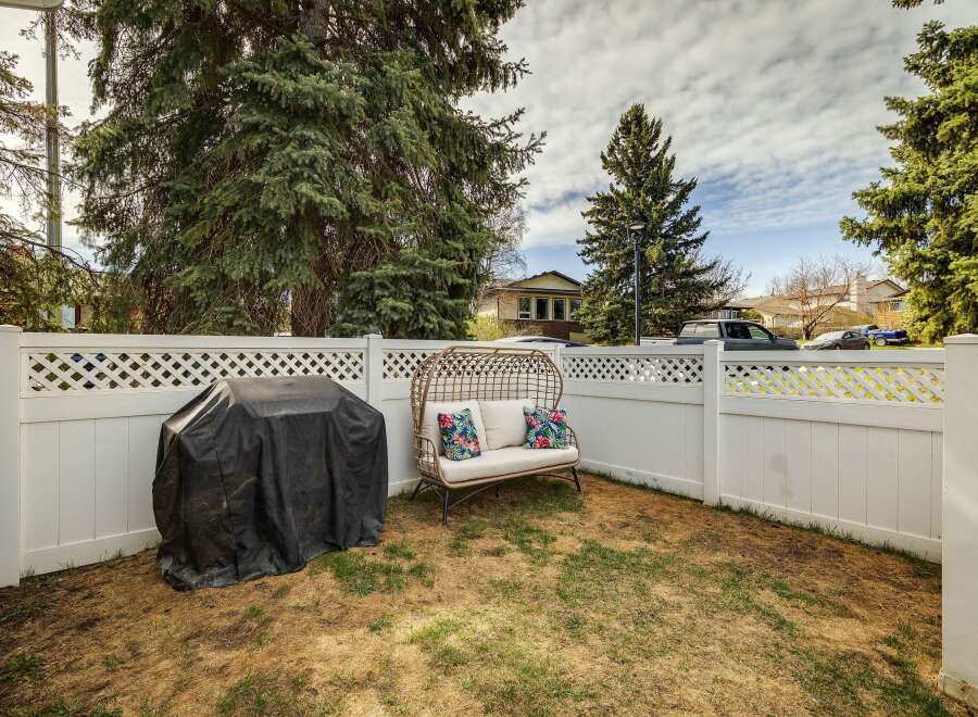 Enjoy outdoor living in this charming backyard oasis! Featuring a cozy seating area, a covered grill, and a pristine white fence, this space is perfect for entertaining or relaxing.