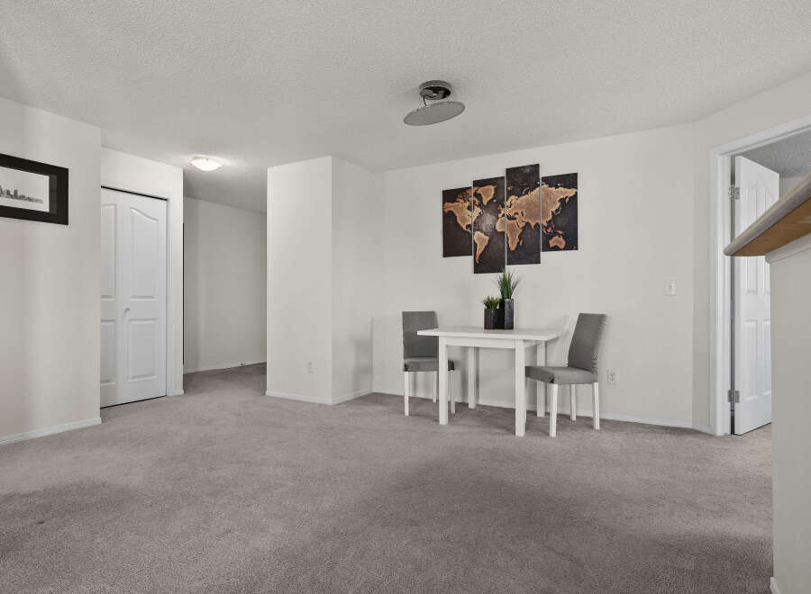 This inviting space features a dining area with a modern white table and two stylish chairs, perfect for intimate meals.