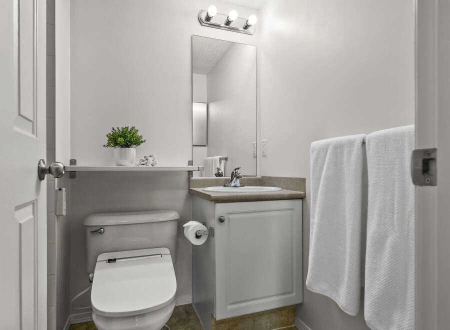This well-maintained bathroom features a modern toilet, a stylish vanity with a sink, and a convenient shelf for storage.