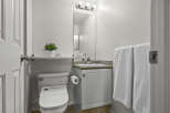 This well-maintained bathroom features a modern toilet, a stylish vanity with a sink, and a convenient shelf for storage.