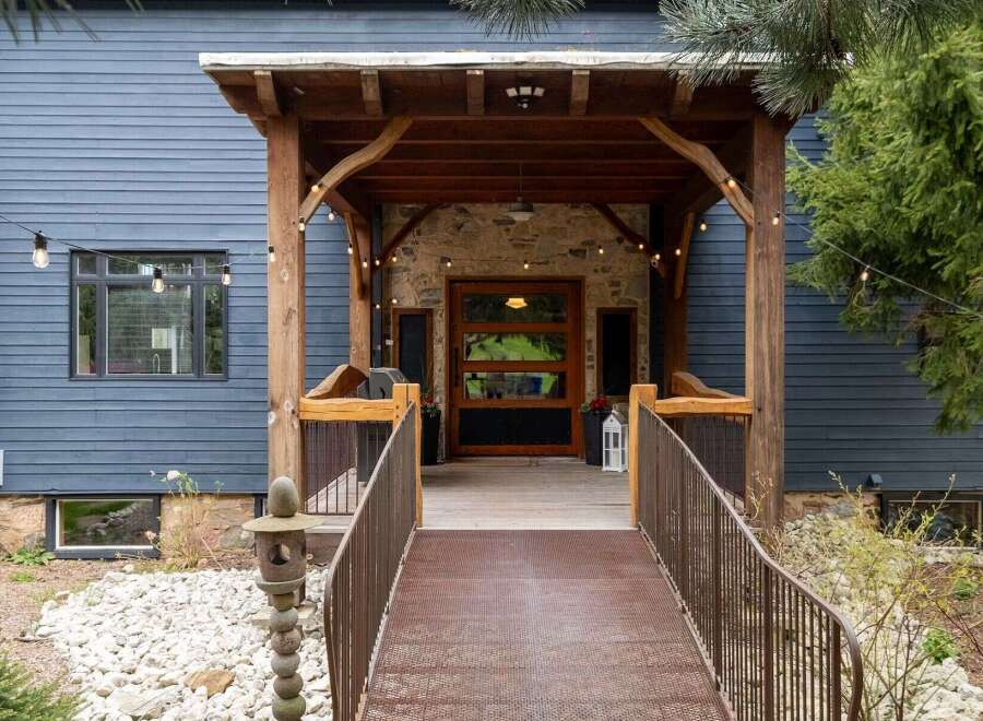 This stunning property boasts a charming entrance with a rustic wooden porch and a welcoming walkway.
