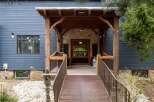 This stunning property boasts a charming entrance with a rustic wooden porch and a welcoming walkway.