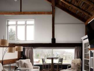 This stunning property boasts a unique architectural design with exposed wooden beams and a vaulted ceiling, creating a spacious and inviting atmosphere.