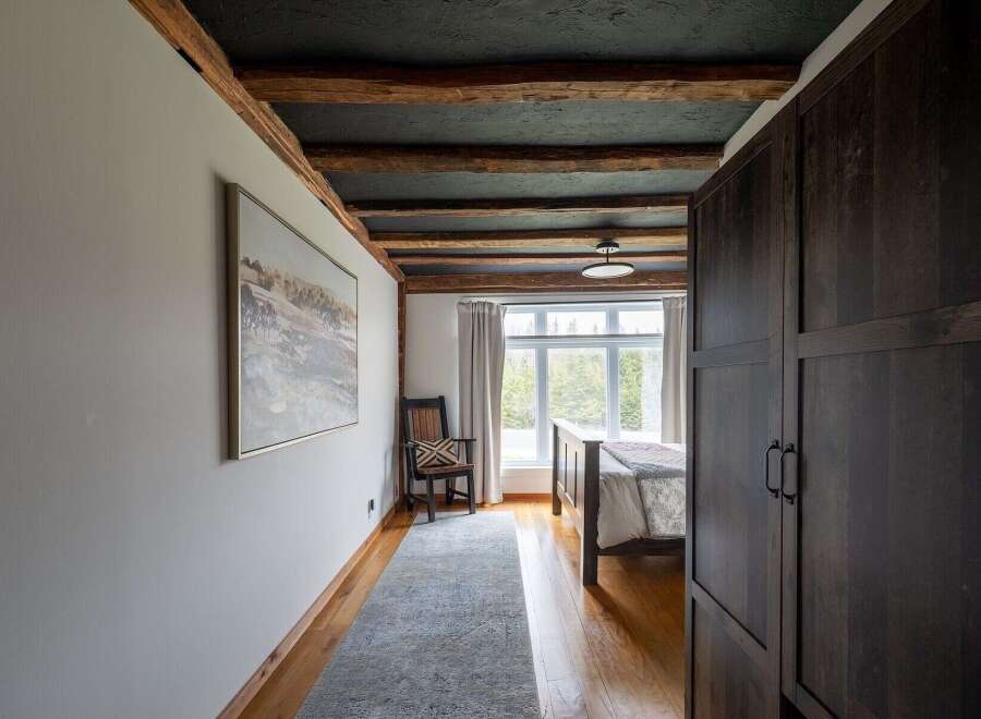 Step into this stunning bedroom featuring exposed wooden beams and a dark, textured ceiling, creating a warm and inviting atmosphere.