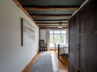 Step into this stunning bedroom featuring exposed wooden beams and a dark, textured ceiling, creating a warm and inviting atmosphere.