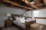 This rustic bedroom showcases a stunning wooden ceiling and a cozy, inviting atmosphere.