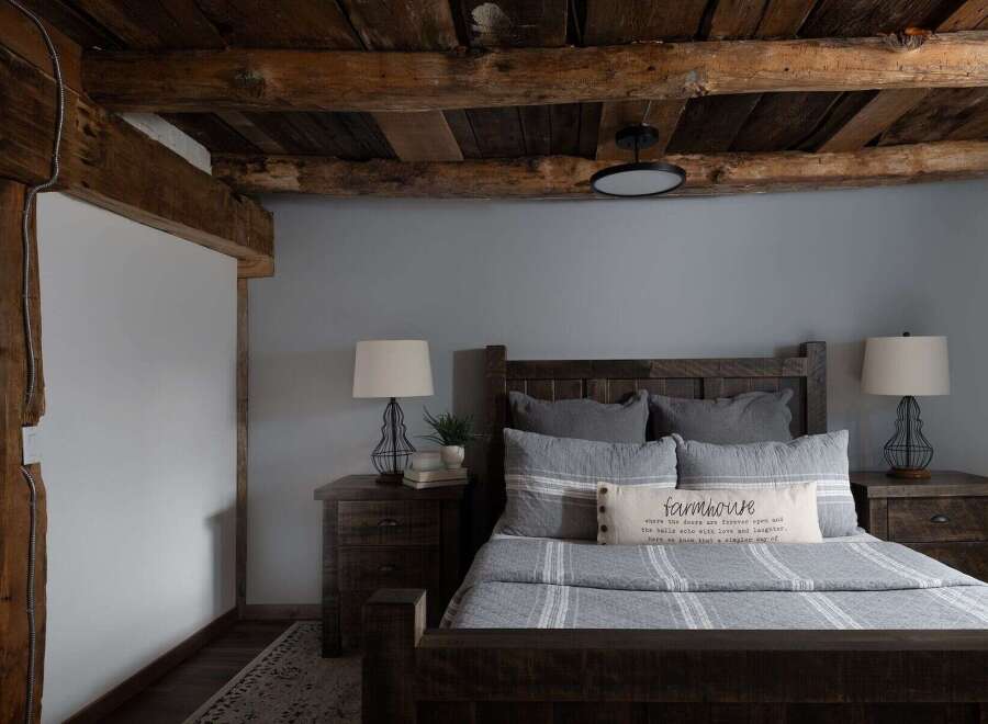 This cozy bedroom features a rustic farmhouse design with exposed wooden beams and a calming gray color scheme.