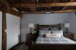 This cozy bedroom features a rustic farmhouse design with exposed wooden beams and a calming gray color scheme.