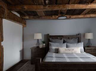 This cozy bedroom features a rustic farmhouse design with exposed wooden beams and a calming gray color scheme.