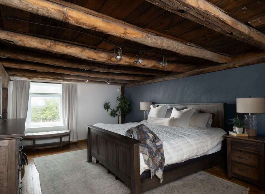 Experience rustic charm in this stunning bedroom featuring exposed wooden beams and a cozy ambiance.