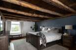 Experience rustic charm in this stunning bedroom featuring exposed wooden beams and a cozy ambiance.