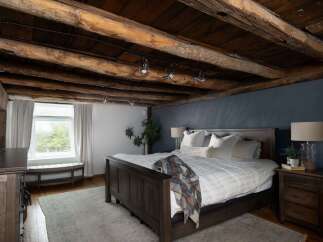 Experience rustic charm in this stunning bedroom featuring exposed wooden beams and a cozy ambiance.