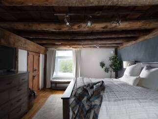This stunning bedroom boasts rustic charm with its exposed wooden beams and cozy ambiance.