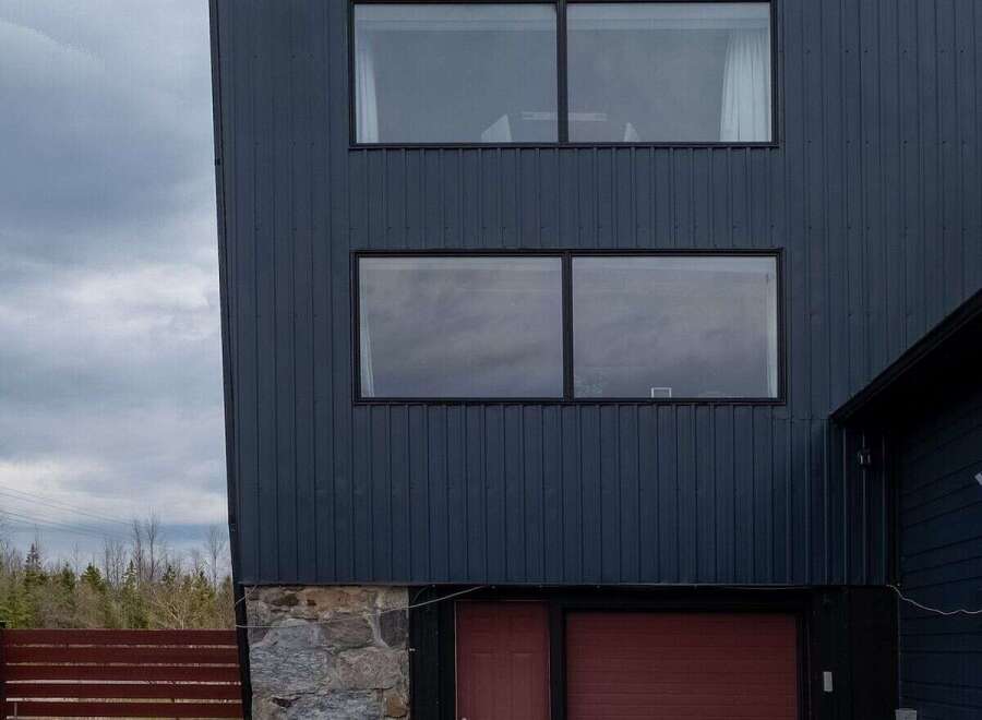 Discover modern living in this stunning property featuring a sleek, dark exterior and contemporary design.