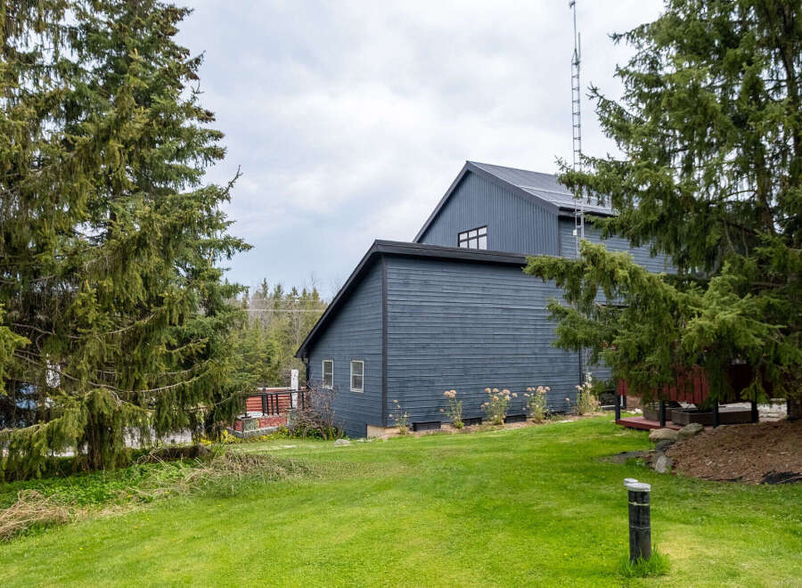 Discover this stunning property featuring a modern, dark-colored exterior and a beautifully landscaped yard.