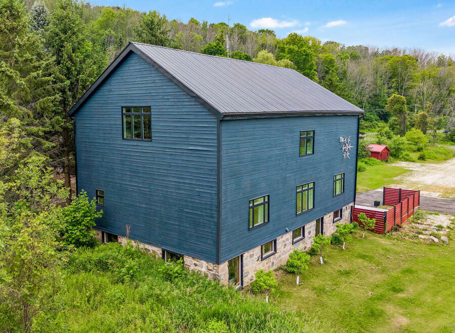 Discover this modern architectural gem featuring a striking dark blue exterior and a durable metal roof.