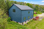 Discover this modern architectural gem featuring a striking dark blue exterior and a durable metal roof.