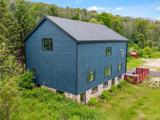 Discover this modern architectural gem featuring a striking dark blue exterior and a durable metal roof.