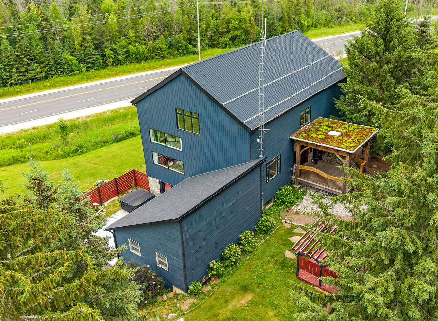 Discover this modern architectural gem featuring a striking dark blue exterior and a unique green roofed gazebo.