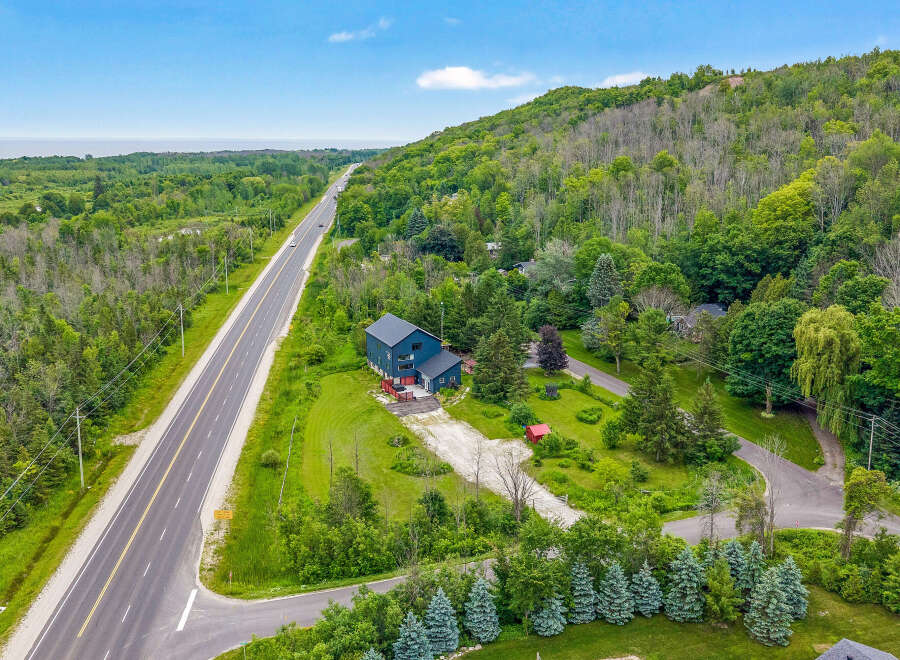 Discover this stunning property featuring a modern dark blue home nestled amidst lush greenery and mature trees.