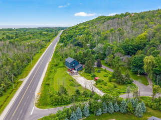 Discover this stunning property featuring a modern dark blue home nestled amidst lush greenery and mature trees.