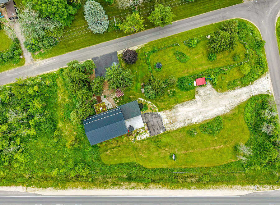 Discover this charming property featuring a modern dark metal roof and a spacious gravel driveway leading to the house.