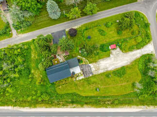 Discover this charming property featuring a modern dark metal roof and a spacious gravel driveway leading to the house.