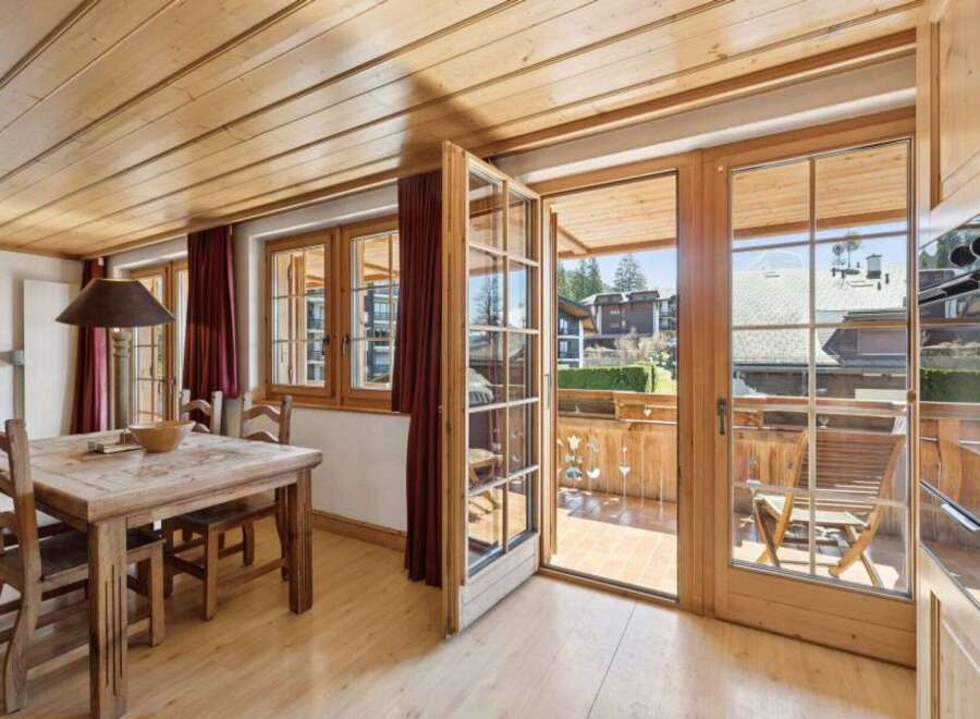Step into this charming property featuring a warm and inviting dining area with a rustic wooden table and chairs.