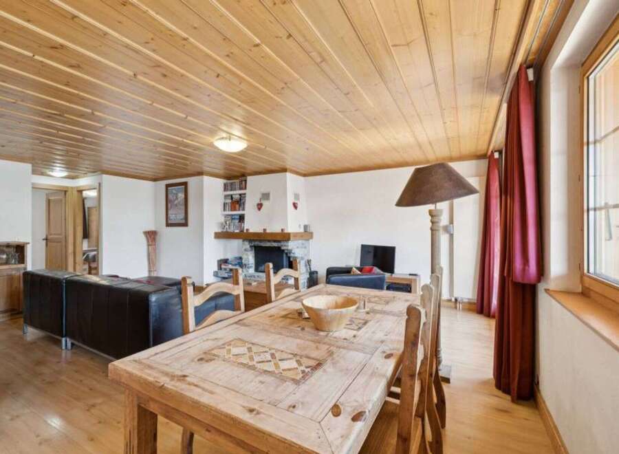 This charming property features a cozy living space with a rustic wooden dining table and chairs, perfect for family gatherings.