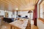 This charming property features a cozy living space with a rustic wooden dining table and chairs, perfect for family gatherings.