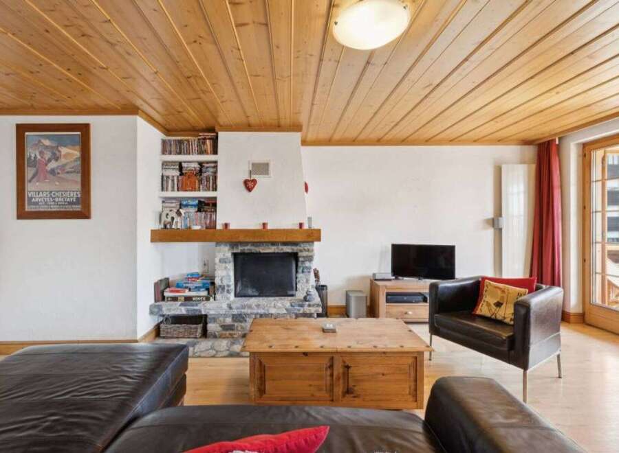 Step into this inviting living space, featuring a cozy fireplace and a warm wooden ceiling.