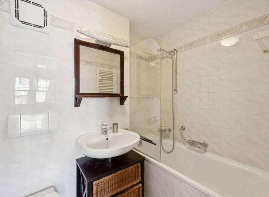 This charming bathroom features a classic design with white tiles and a functional layout.