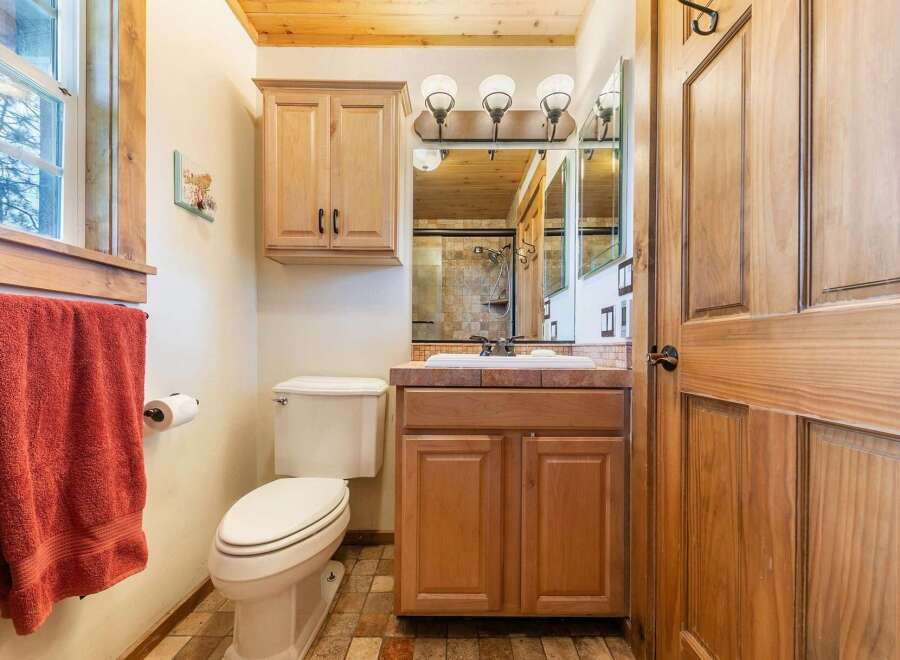 This charming bathroom features a warm, inviting ambiance with its wooden cabinetry and trim.