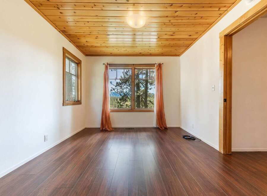 Step into this inviting space, featuring a warm wooden ceiling and rich hardwood floors.