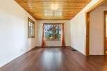 Step into this inviting space, featuring a warm wooden ceiling and rich hardwood floors.