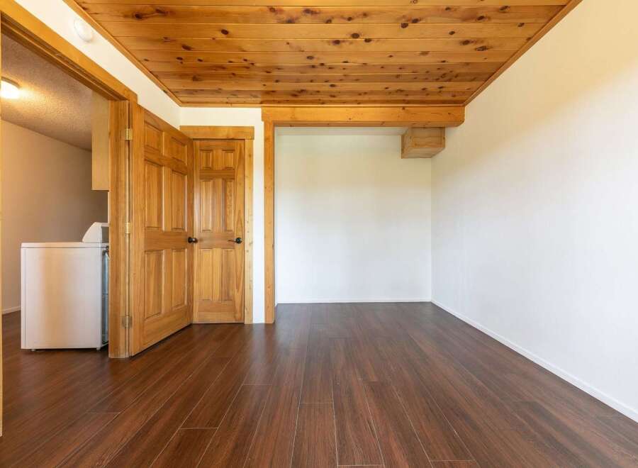 Discover the charm of this inviting space, featuring a warm wooden ceiling and rich, dark wood flooring.