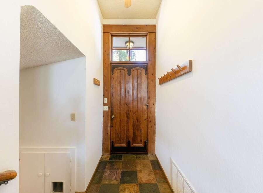 Step into this inviting entryway, showcasing a stunning wooden door and a unique slate tile floor.