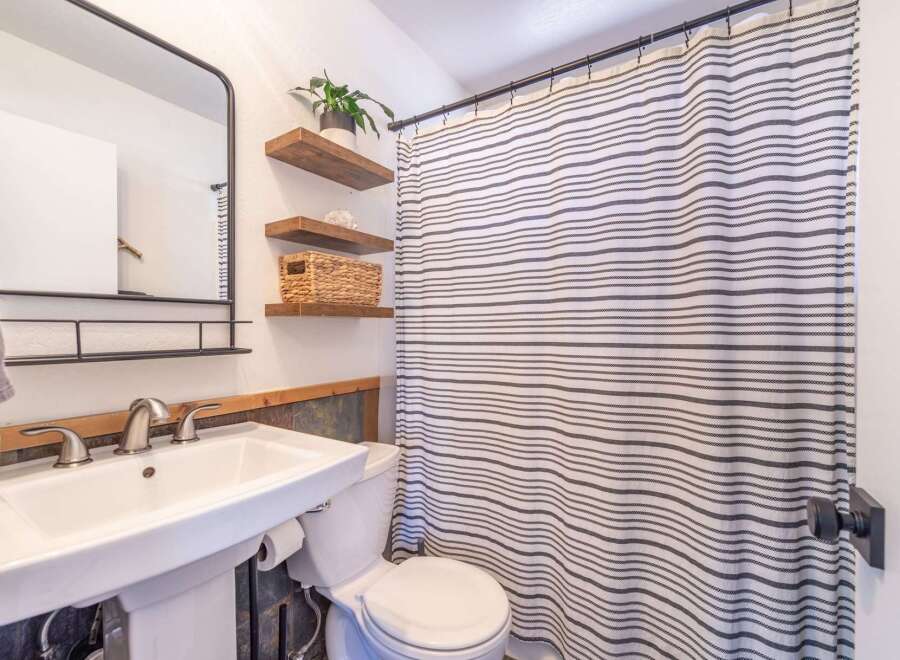 This charming bathroom features a modern design with a pedestal sink and a stylish shower curtain.
