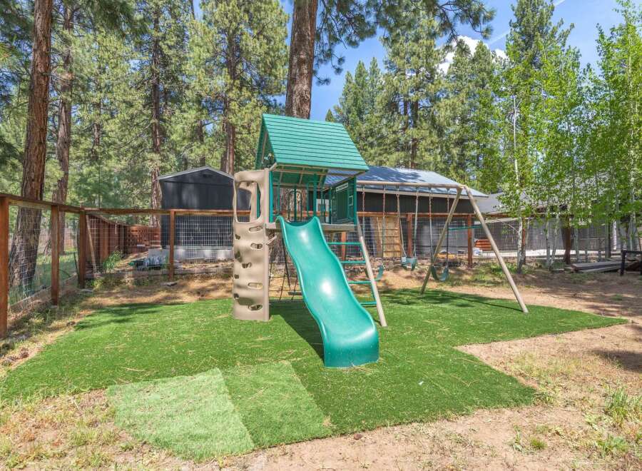 Enjoy outdoor fun in this property's backyard, featuring a playground with a slide and swings.