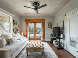 Step into this charming living space, featuring a cozy daybed and a stylish tufted ottoman.