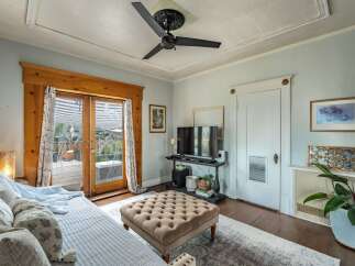 Step into this inviting living space, featuring a stylish ottoman and a sleek TV setup.