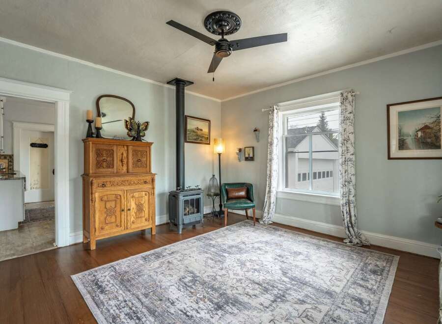 Step into this charming living space, featuring a cozy wood-burning stove and a beautiful antique cabinet.