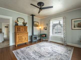Step into this charming living space, featuring a cozy wood-burning stove and a beautiful antique cabinet.