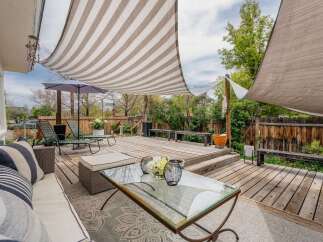 Enjoy outdoor living at its finest in this stunning property! This home features a beautifully designed deck with a stylish striped canopy, perfect for relaxing or entertaining.