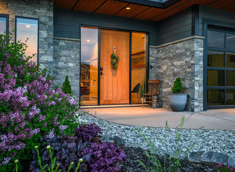 This stunning property boasts a modern facade with a beautiful stone exterior and a welcoming wooden door.
