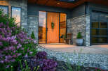 This stunning property boasts a modern facade with a beautiful stone exterior and a welcoming wooden door.