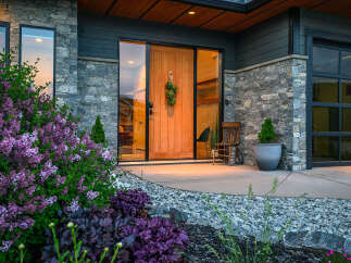 This stunning property boasts a modern facade with a beautiful stone exterior and a welcoming wooden door.